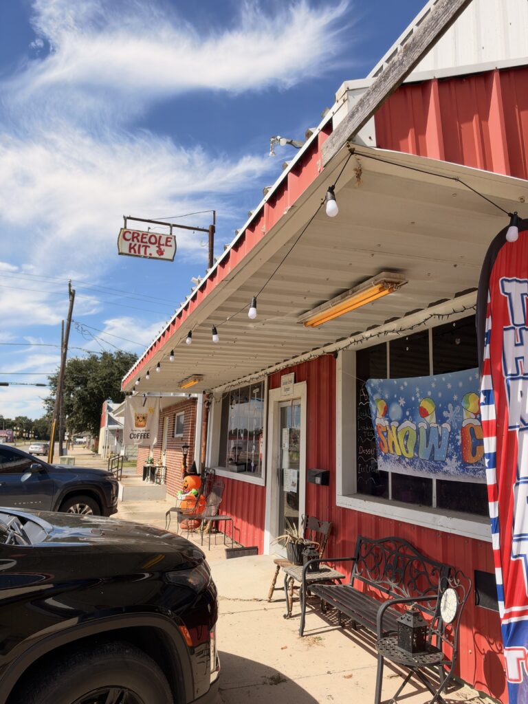 Store Front of the Poolhall Cafe and Sip and Thrift. Red storefront with decorative signs.